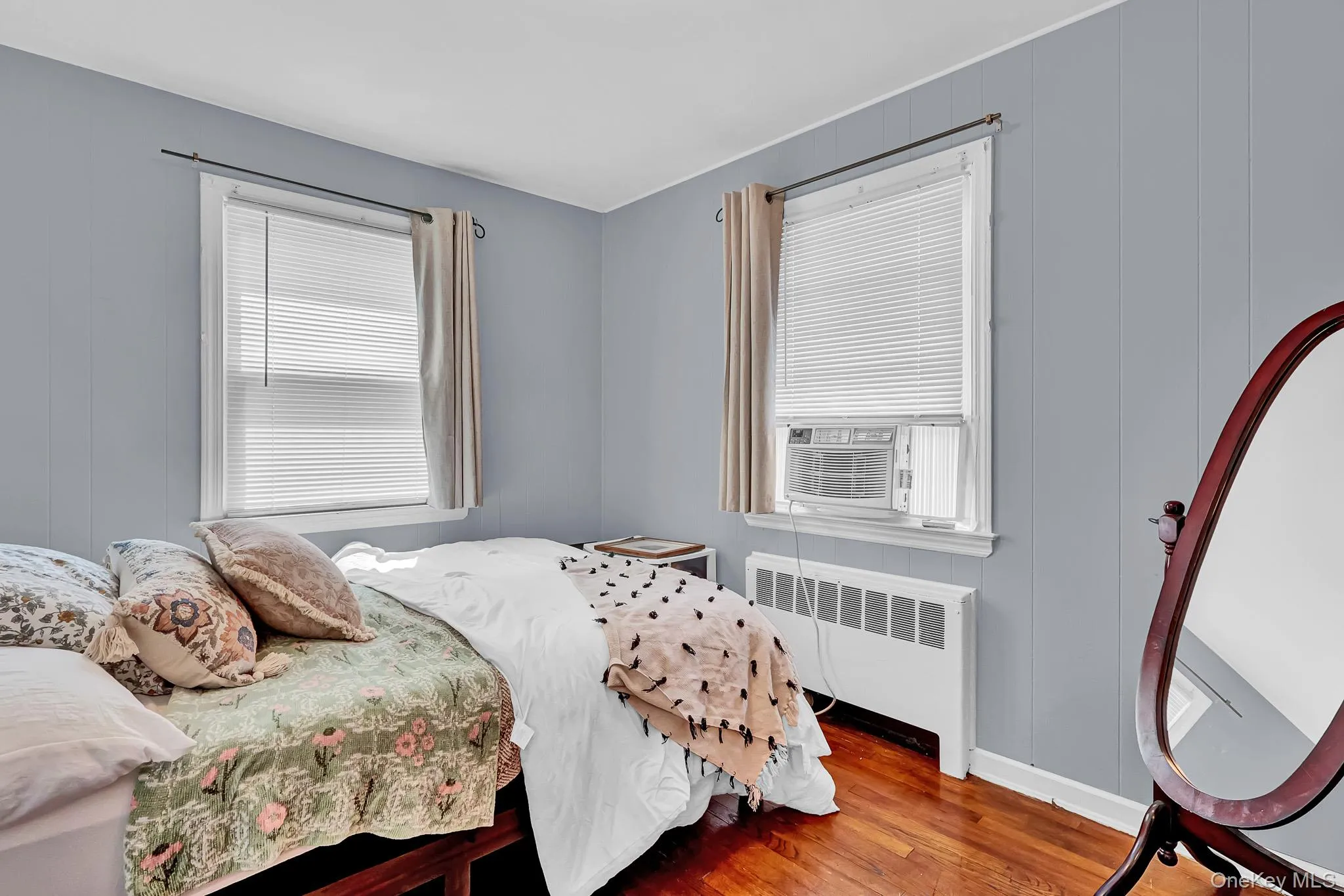 Wood-finish flooring, two windows with blinds, and light-toned wall paneling Wood-finish flooring, two windows with blinds, and light-toned wall paneling