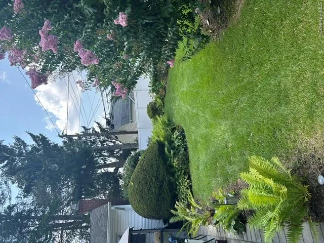 Expansive backyard featuring a manicured lawn, established landscaping, and a paver patio Expansive backyard featuring a manicured lawn, established landscaping, and a paver patio