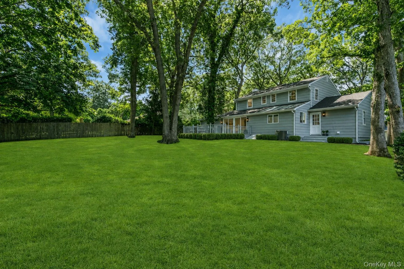 Expansive green lawn, mature trees, privacy fencing, multi-level siding exterior, and a rear patio Expansive green lawn, mature trees, privacy fencing, multi-level siding exterior, and a rear patio
