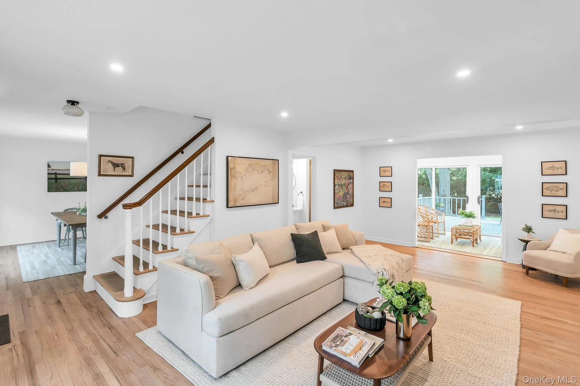 Hardwood flooring throughout, recessed lighting, and a white staircase with wood handrail Hardwood flooring throughout, recessed lighting, and a white staircase with wood handrail