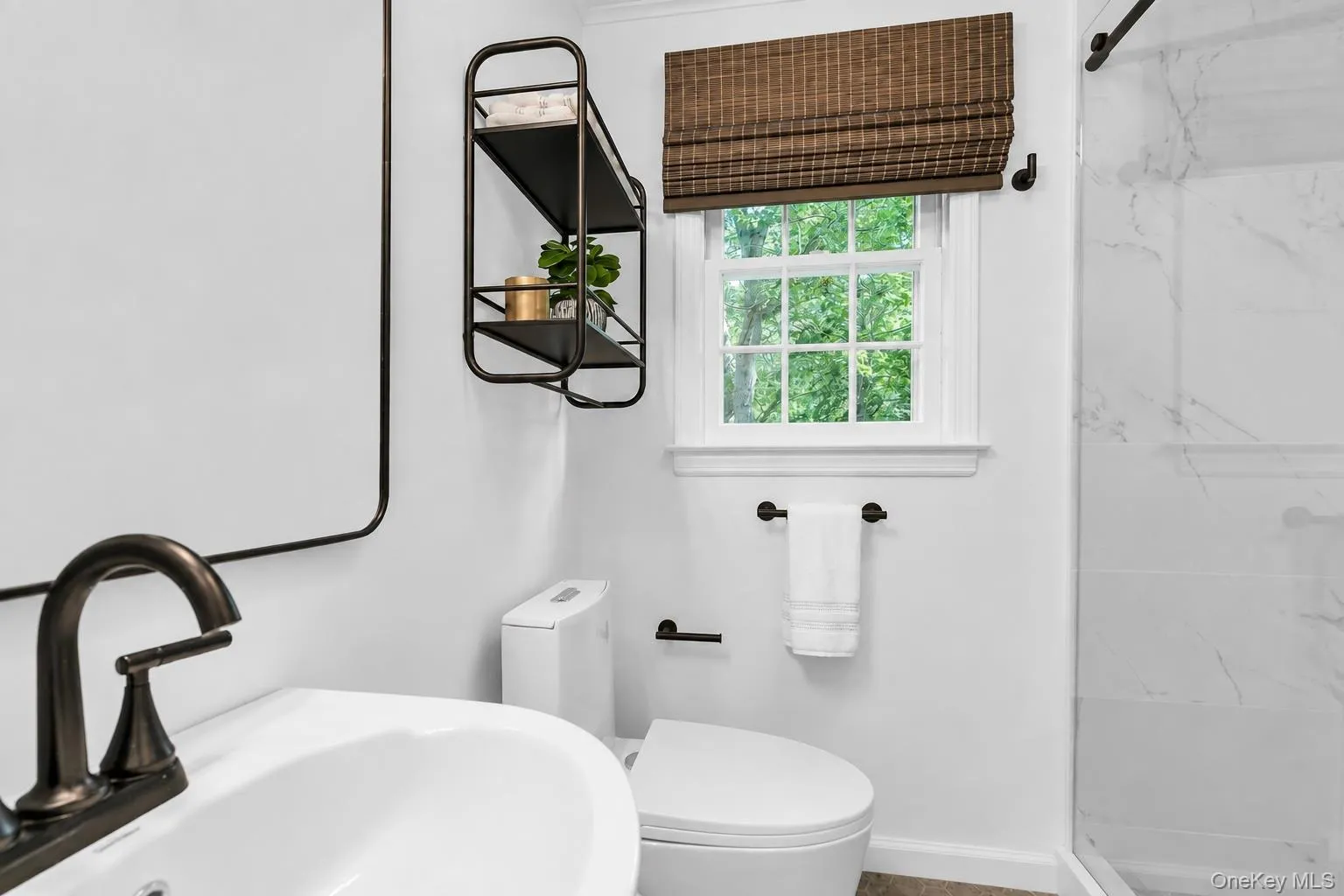 Bathroom featuring a white ceramic vessel sink, matte black finish faucet, and a wall-mounted shelving unit Bathroom featuring a white ceramic vessel sink, matte black finish faucet, and a wall-mounted shelving unit