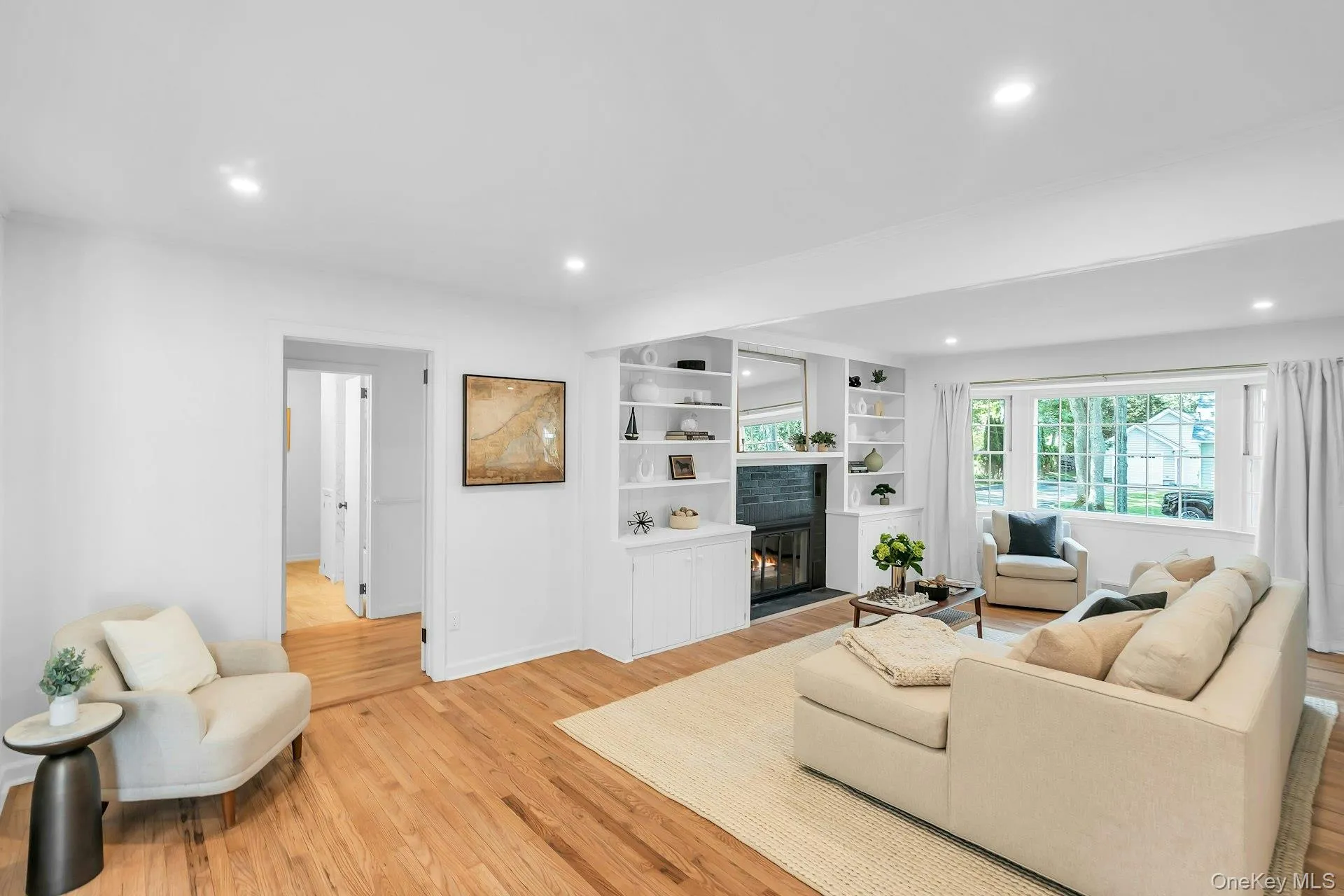 Recessed lighting illuminates the living area, featuring wood-finish flooring and a fireplace with built-in shelving Recessed lighting illuminates the living area, featuring wood-finish flooring and a fireplace with built-in shelving