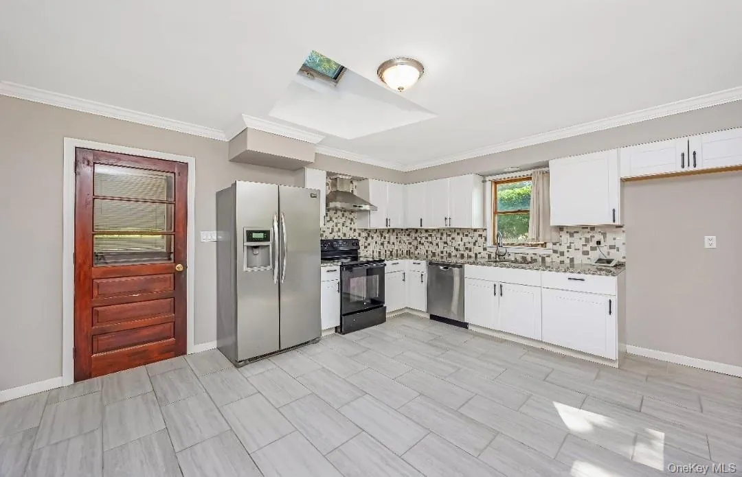 Kitchen featuring white shaker cabinetry, stainless steel appliances, mosaic tile backsplash, and light-toned tile flooring Kitchen featuring white shaker cabinetry, stainless steel appliances, mosaic tile backsplash, and light-toned tile flooring