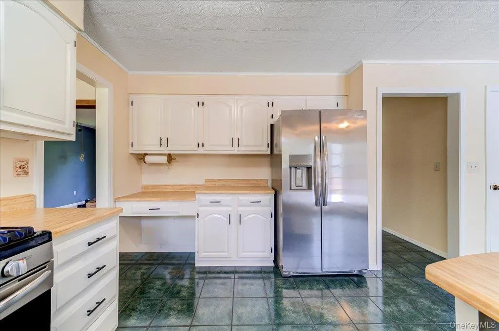 Country Kitchen with White cabinetry, Butcher Block countertops, stainless steel appliances, Dark Green Floor Tiles Country Kitchen with White cabinetry, Butcher Block countertops, stainless steel appliances, Dark Green Floor Tiles
