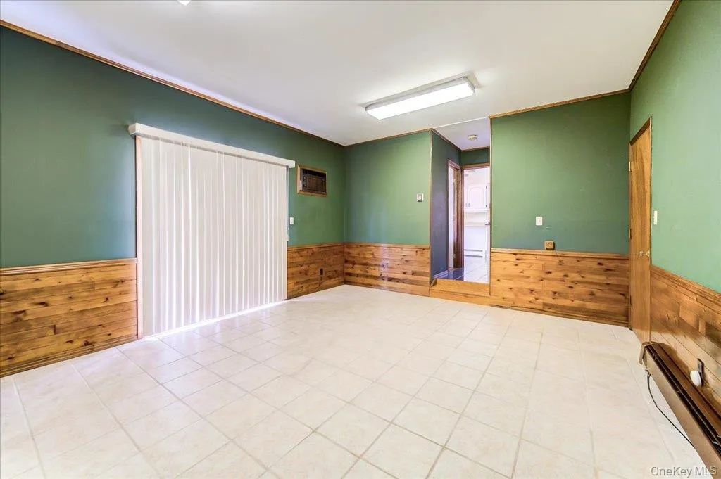Spacious family room Hardwood chair rails, White tiled floor, sliding glass doors to backyard brick patio adjacent to deck Spacious family room Hardwood chair rails, White tiled floor, sliding glass doors to backyard brick patio adjacent to deck