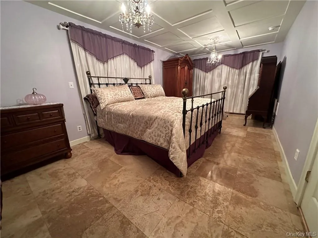 Bedroom with a notable chandelier and coffered ceiling Bedroom with a notable chandelier and coffered ceiling