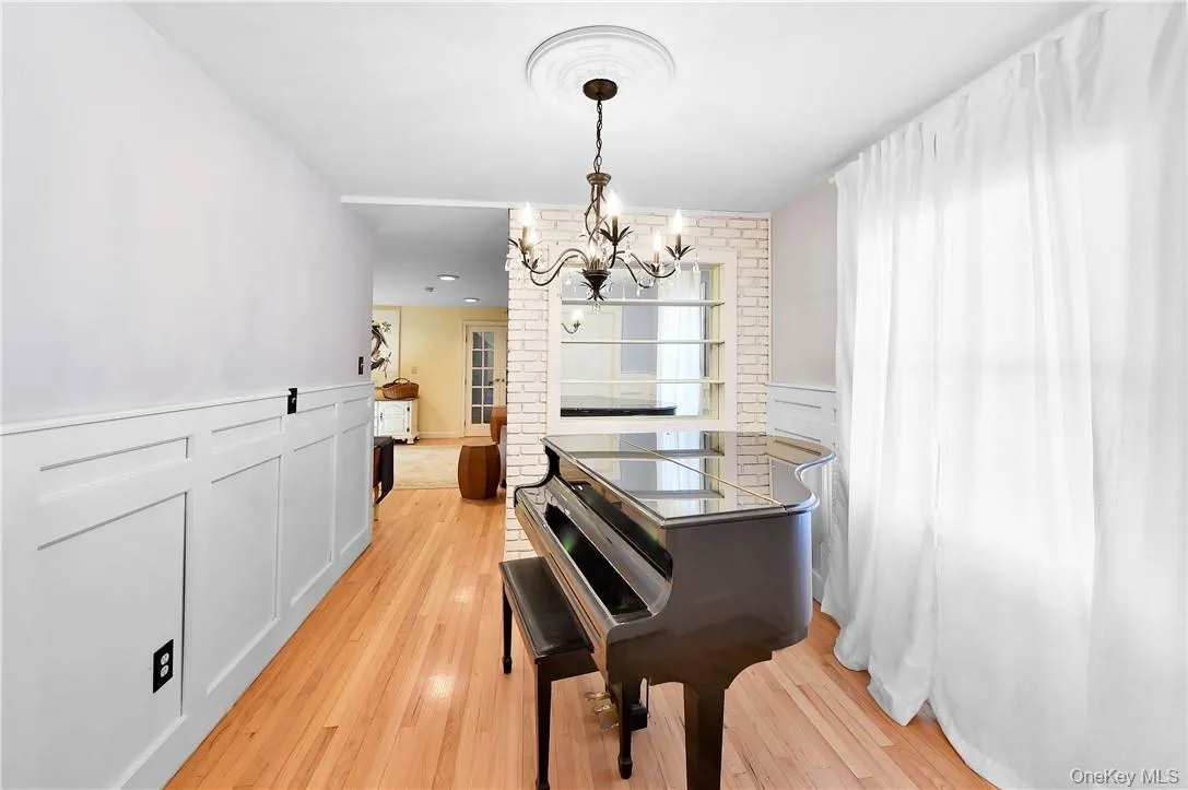 Miscellaneous room with brick wall, light hardwood / wood-style flooring, and an inviting chandelier Miscellaneous room with brick wall, light hardwood / wood-style flooring, and an inviting chandelier
