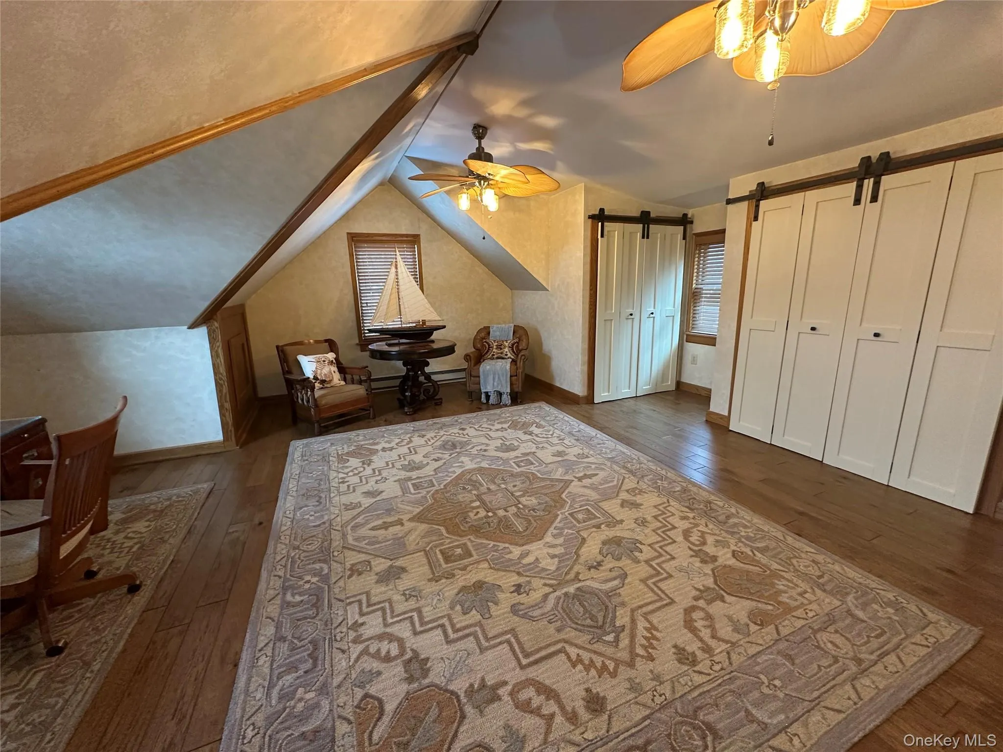 Bonus room featuring dark wood-type flooring, ceiling fan, a barn door, and vaulted ceiling Bonus room featuring dark wood-type flooring, ceiling fan, a barn door, and vaulted ceiling