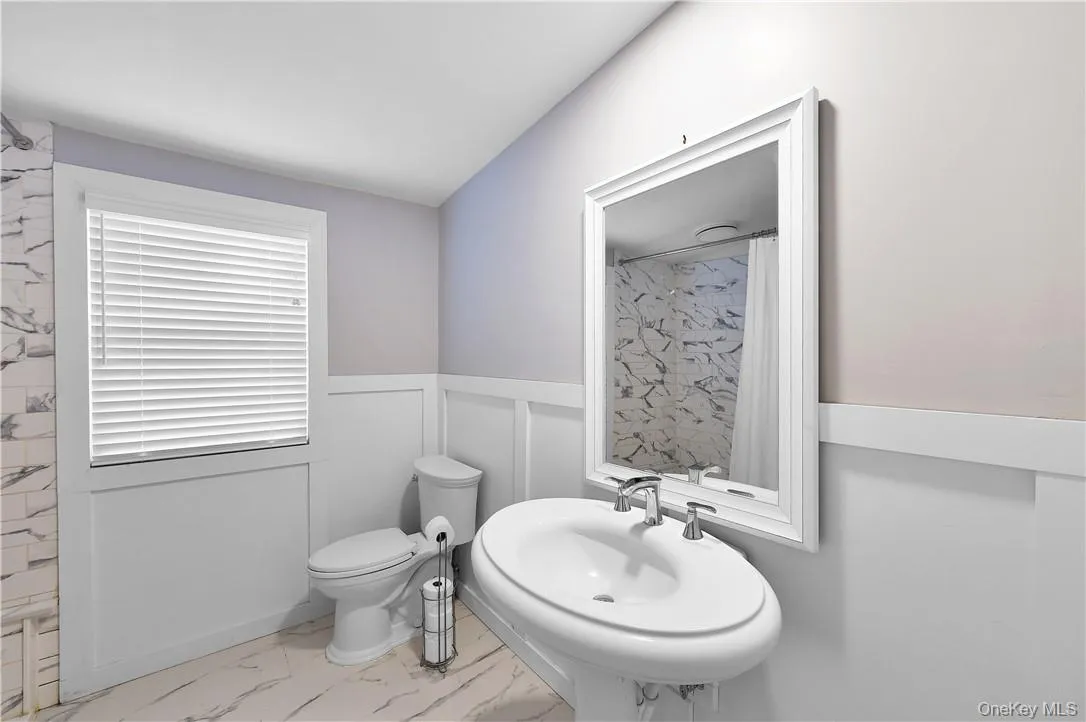 Bathroom featuring toilet, sink, and a shower with curtain Bathroom featuring toilet, sink, and a shower with curtain