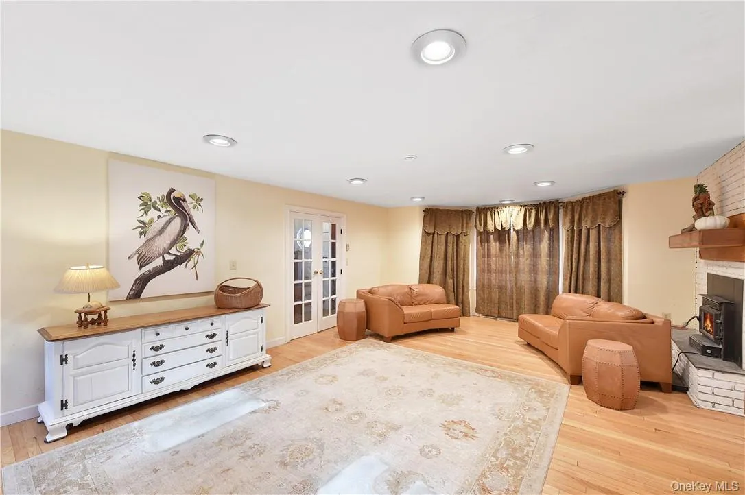 Living room with french doors, light hardwood / wood-style flooring, and a wood stove Living room with french doors, light hardwood / wood-style flooring, and a wood stove
