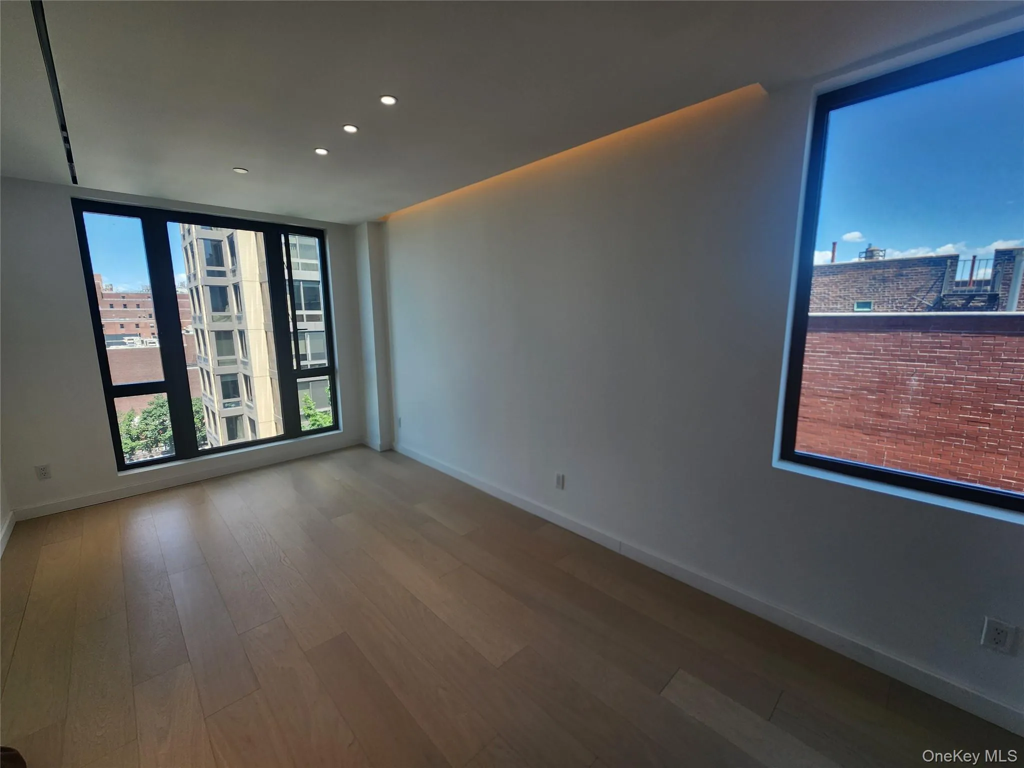 Recessed ceiling lighting, a coved lighting feature, wood-finish flooring, and large windows with black frames Recessed ceiling lighting, a coved lighting feature, wood-finish flooring, and large windows with black frames