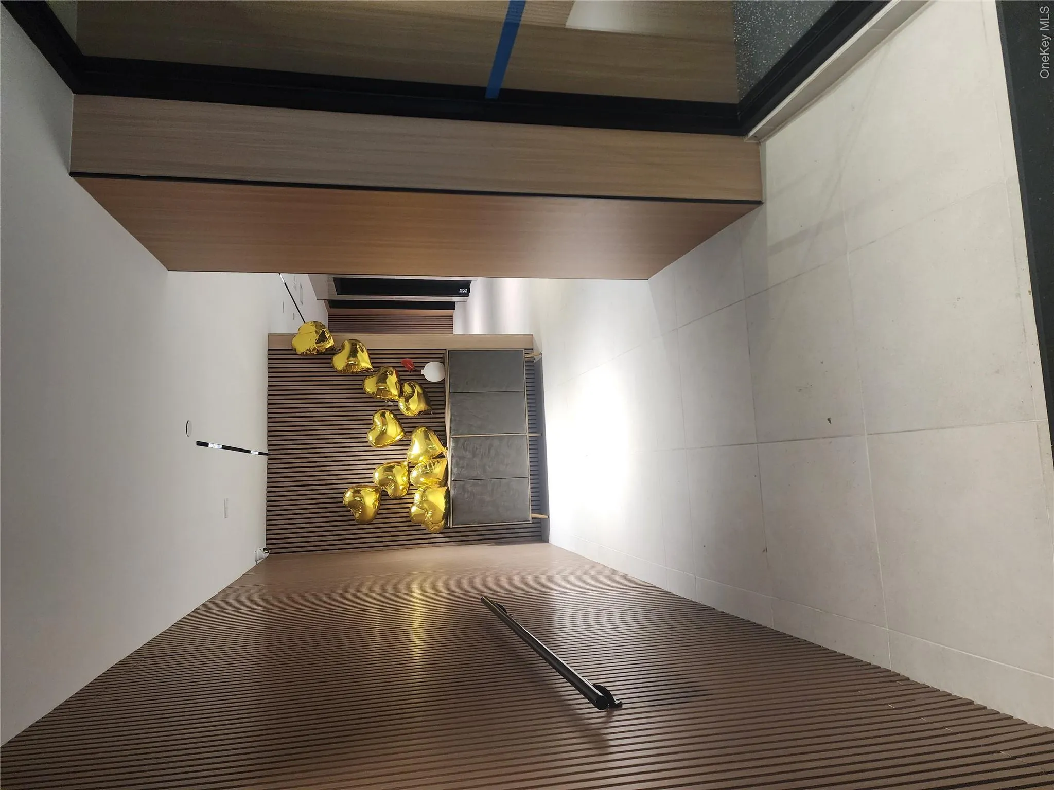 Wood-finish slatted wall panels, recessed lighting, and large format floor tiles Wood-finish slatted wall panels, recessed lighting, and large format floor tiles