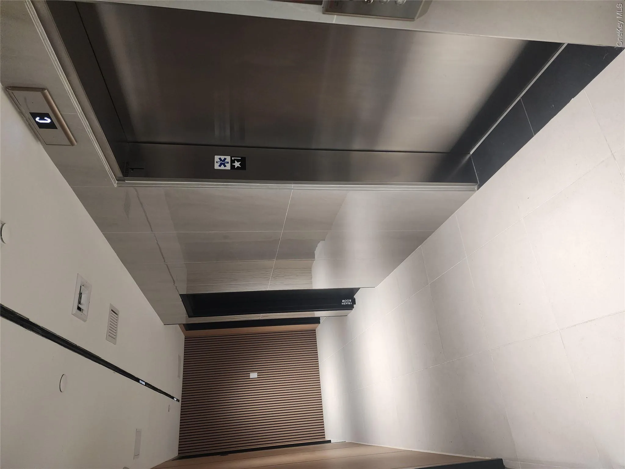 Modern elevator access with brushed metal doors and light-toned tile flooring Modern elevator access with brushed metal doors and light-toned tile flooring