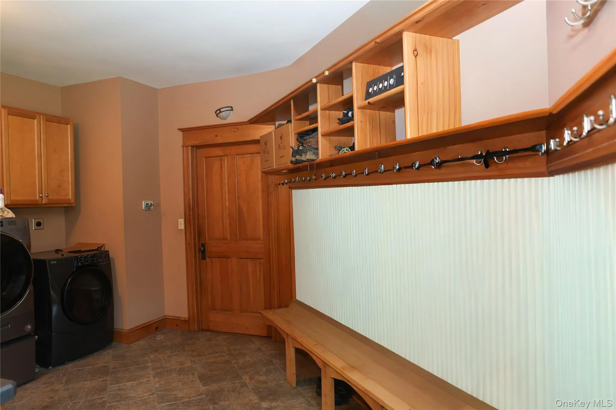Built-in wood shelving, integrated wood bench, wood-finish flooring, wood cabinetry, and a wood door with trim Built-in wood shelving, integrated wood bench, wood-finish flooring, wood cabinetry, and a wood door with trim