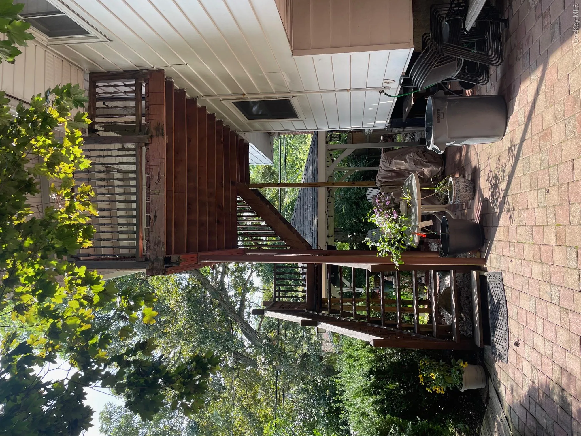Multi-level wood deck with staircase, brick paver patio, and white siding exterior Multi-level wood deck with staircase, brick paver patio, and white siding exterior