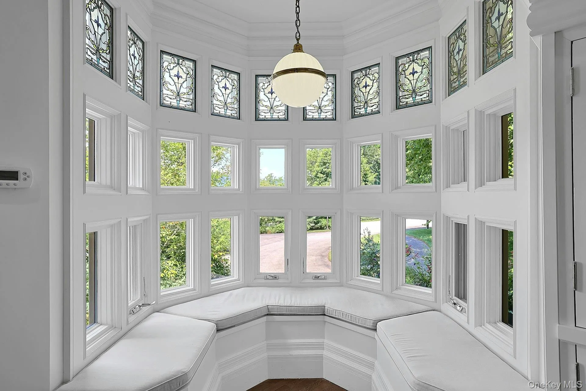This cozy, bright bay window seat is an amazing spot to laze and read. The stained glass detail on the windows of the tower, which continues up to the second floor, are illuminated by the beautiful globe fixture. This cozy, bright bay window seat is an amazing spot to laze and read. The stained glass detail on the windows of the tower, which continues up to the second floor, are illuminated by the beautiful globe fixture.