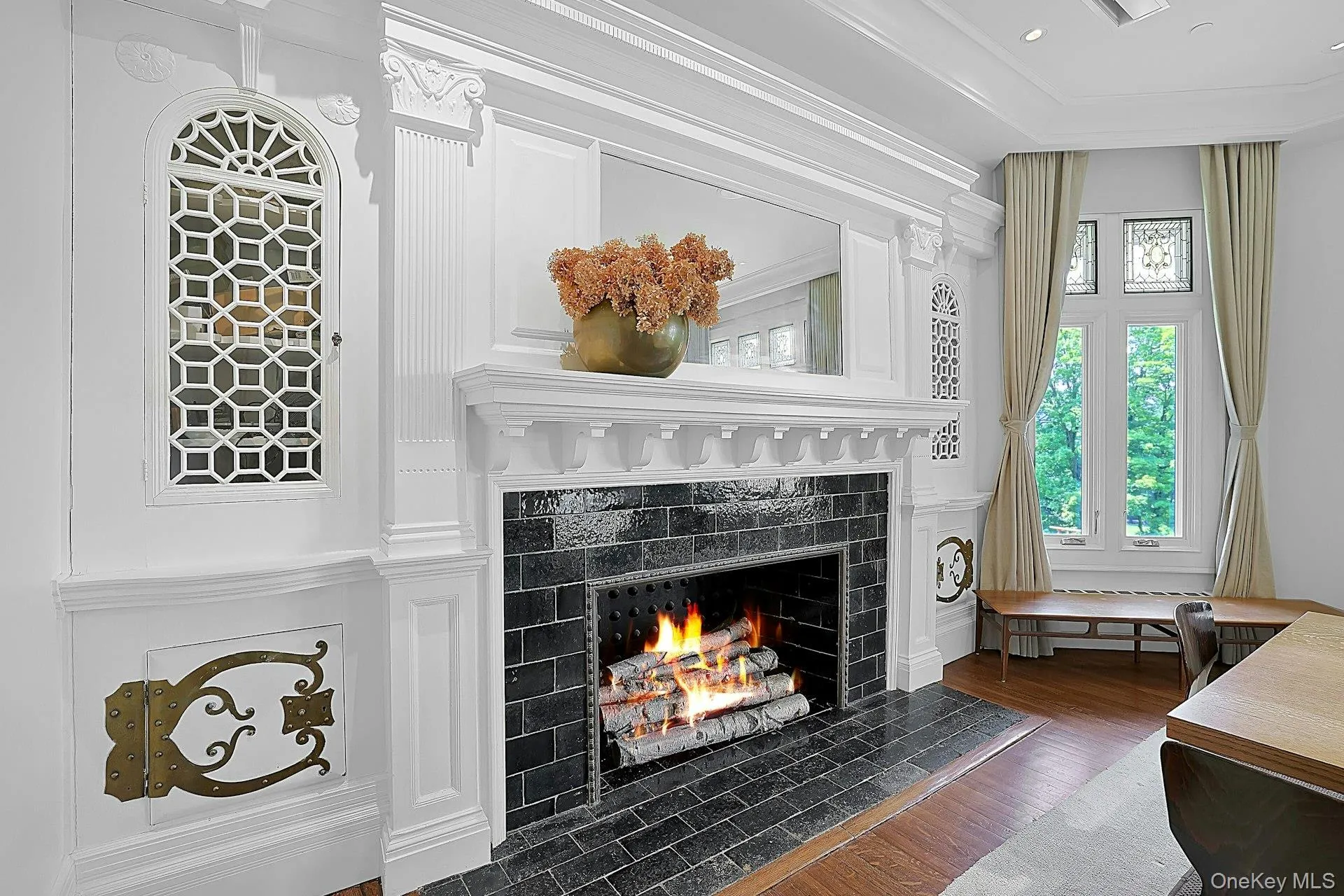 At the head of the dining room is another dramatic fireplace, with original tile. It is surrounded by intricate woodwork on the mantel and pilasters. Notice the intricate metal work for the firewood cabinets. At the head of the dining room is another dramatic fireplace, with original tile. It is surrounded by intricate woodwork on the mantel and pilasters. Notice the intricate metal work for the firewood cabinets.