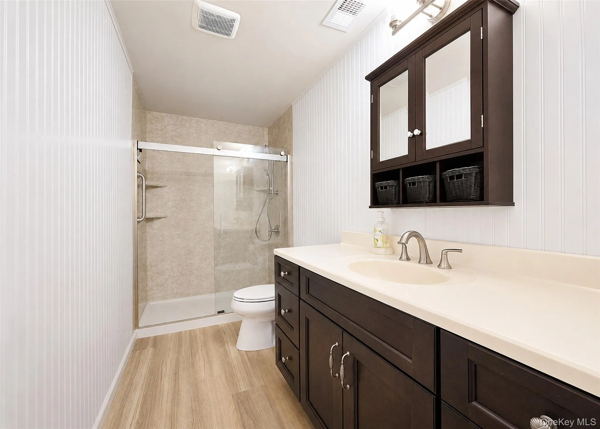 Beautiful, Recently Redone, Full Bath With A Large Vanity, Fiberglass Walk-In Shower Surround, Frameless Shower Door, Wainscotting, & New Wide-Plank Oak Laminate Flooring. Beautiful, Recently Redone, Full Bath With A Large Vanity, Fiberglass Walk-In Shower Surround, Frameless Shower Door, Wainscotting, & New Wide-Plank Oak Laminate Flooring.