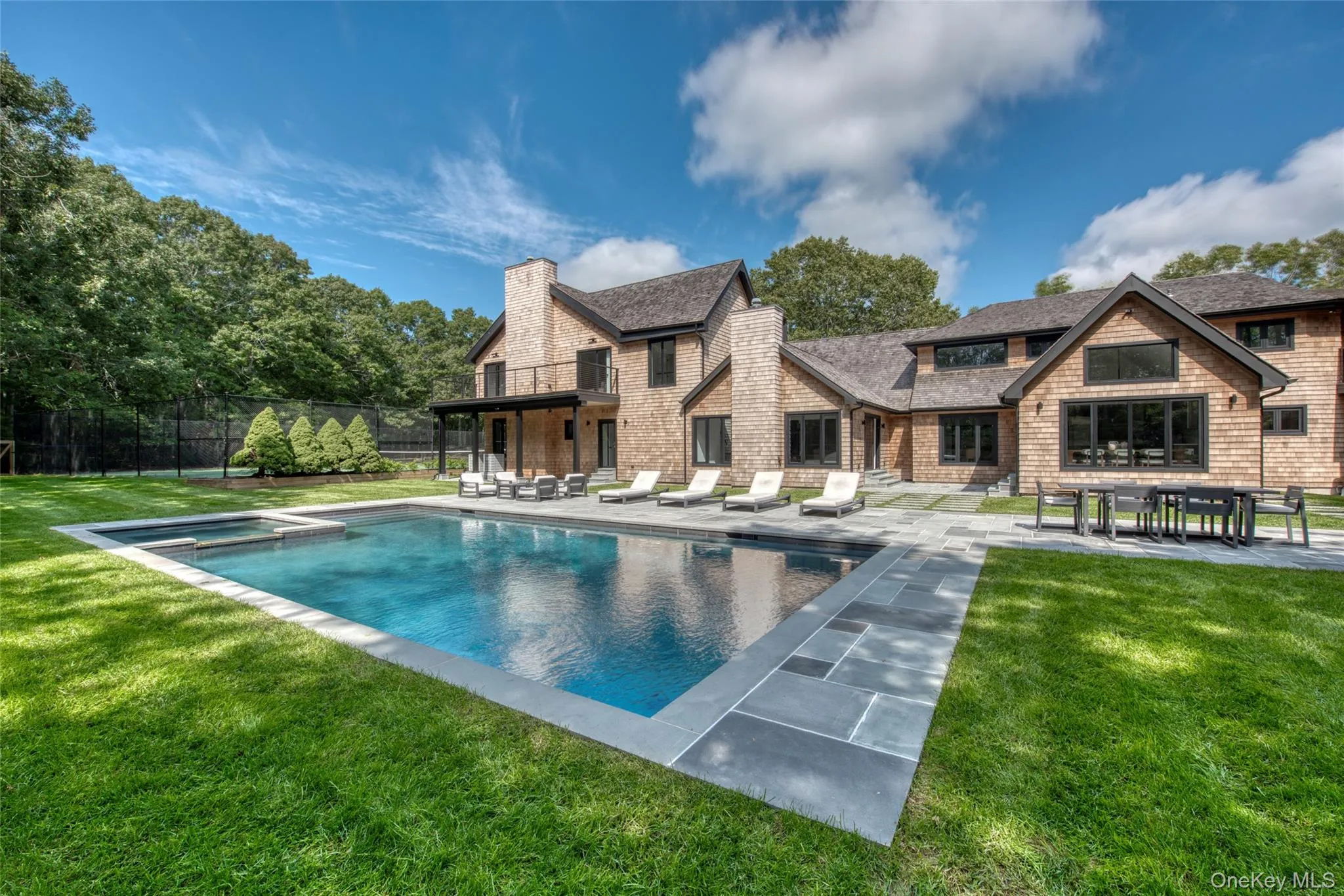 Expansive backyard featuring a rectangular swimming pool, integrated spa, and large stone patio