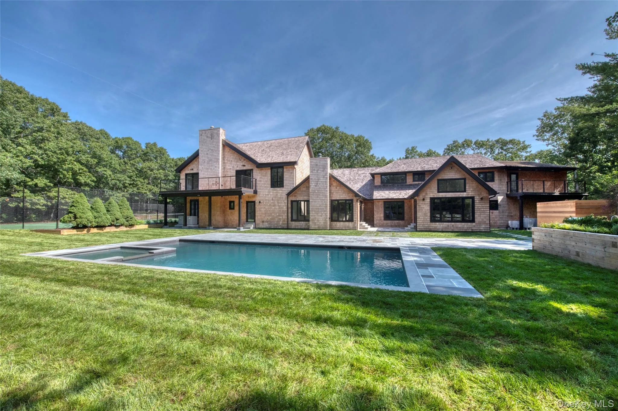 Expansive backyard featuring a rectangular swimming pool, stone coping, and a surrounding lawn Expansive backyard featuring a rectangular swimming pool, stone coping, and a surrounding lawn