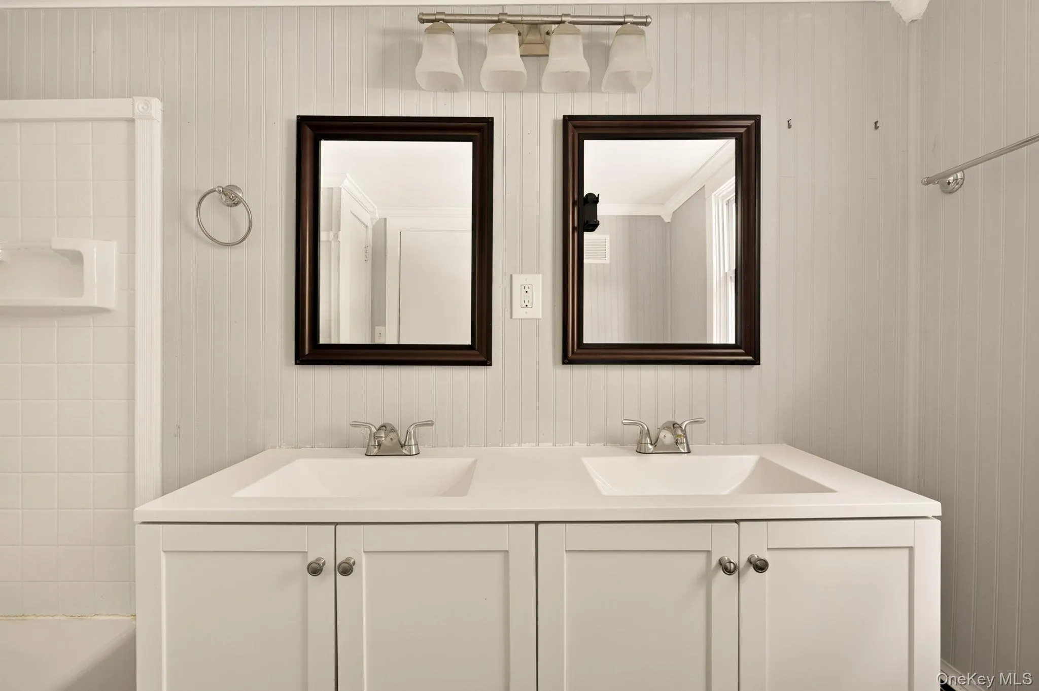 Double vanity with integrated sinks, white cabinetry, and individual framed mirrors Double vanity with integrated sinks, white cabinetry, and individual framed mirrors