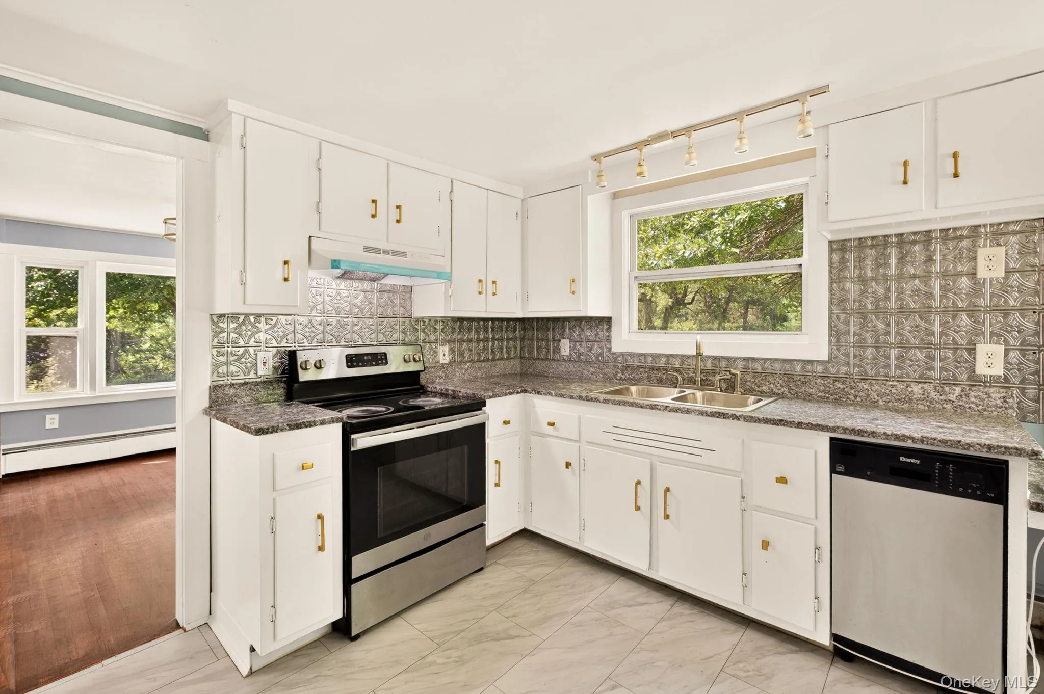 Kitchen featuring white cabinetry, stainless steel appliances, granite-look countertops, and a decorative tile backsplash Kitchen featuring white cabinetry, stainless steel appliances, granite-look countertops, and a decorative tile backsplash