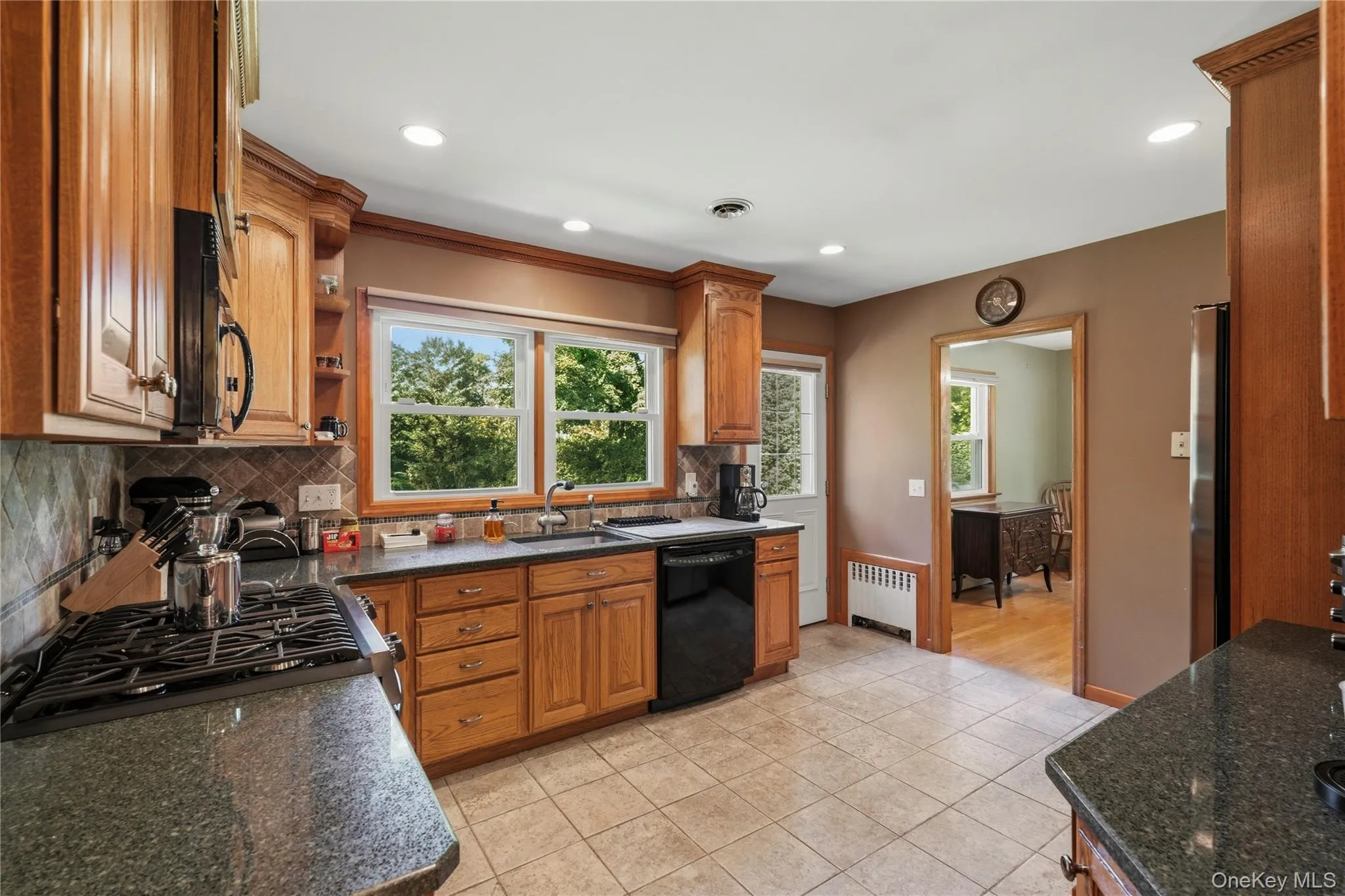 Kitchen featuring wood cabinetry, granite countertops, tile flooring, and recessed lighting Kitchen featuring wood cabinetry, granite countertops, tile flooring, and recessed lighting