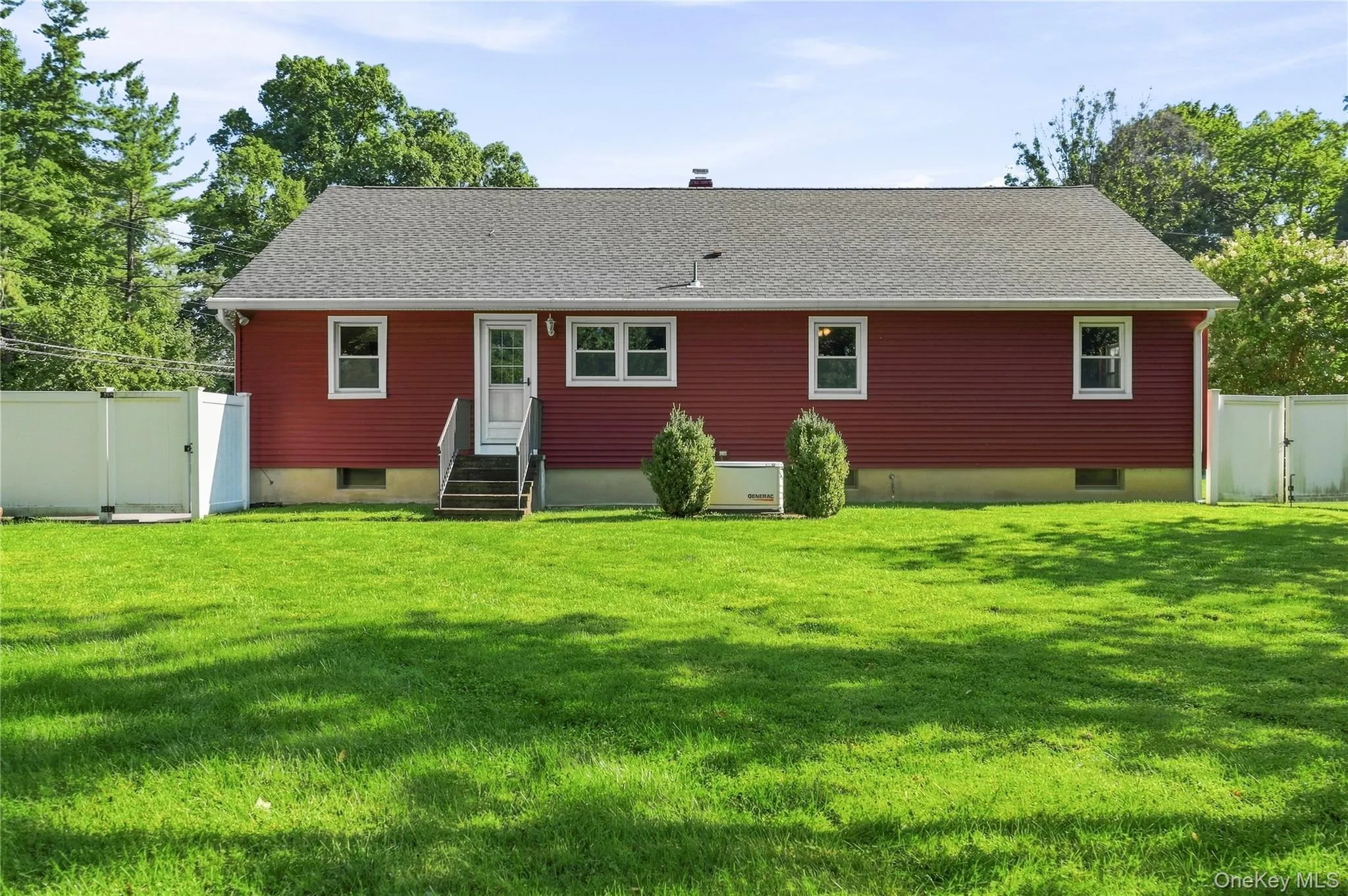 Expansive rear yard with green lawn, red siding, white trim windows, and a privacy fence Expansive rear yard with green lawn, red siding, white trim windows, and a privacy fence