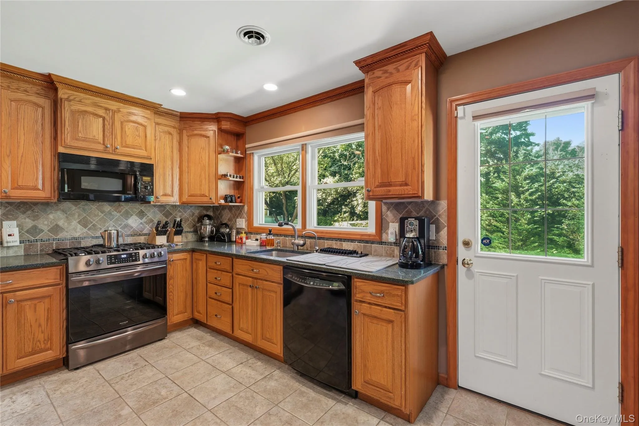 Kitchen featuring wood cabinetry, stainless steel range, built-in microwave, and tile backsplash Kitchen featuring wood cabinetry, stainless steel range, built-in microwave, and tile backsplash