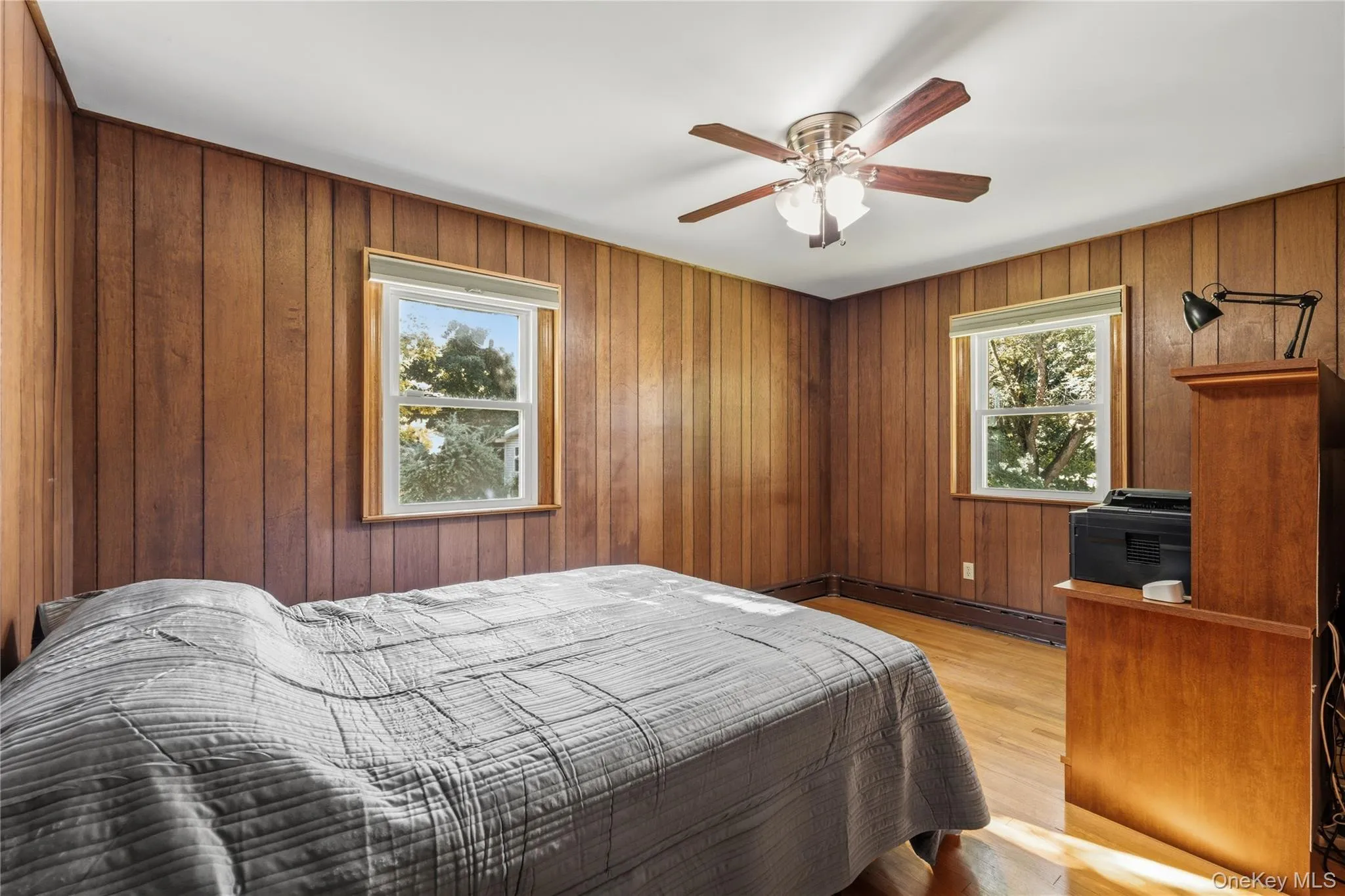 Wood-finish wall paneling with hardwood flooring and two windows Wood-finish wall paneling with hardwood flooring and two windows