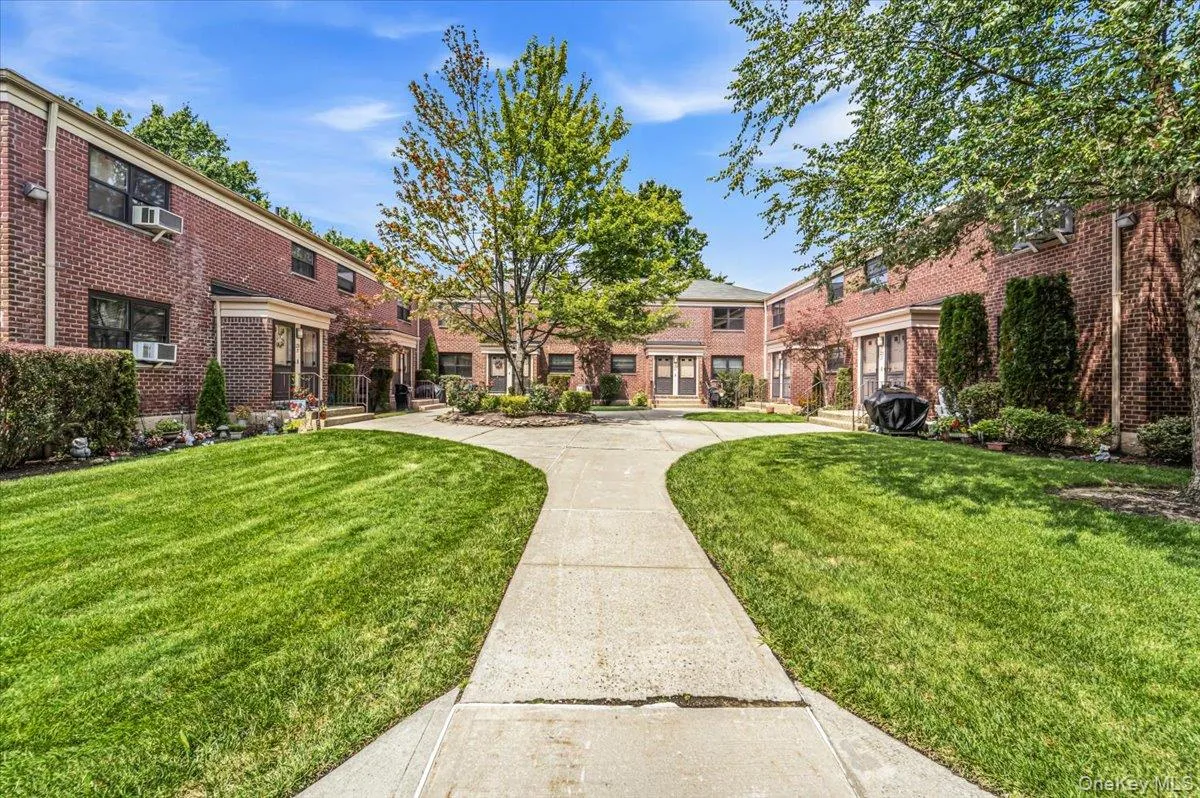 Brick exterior with multiple windows, concrete walkway, and expansive green lawn areas Brick exterior with multiple windows, concrete walkway, and expansive green lawn areas