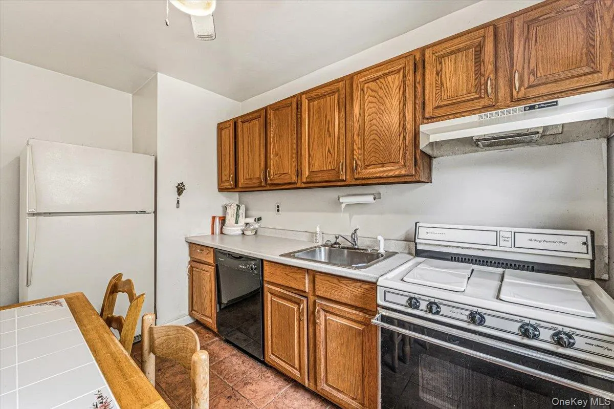 Functional kitchen featuring wood-finish cabinetry, white countertops, and a stainless steel sink Functional kitchen featuring wood-finish cabinetry, white countertops, and a stainless steel sink