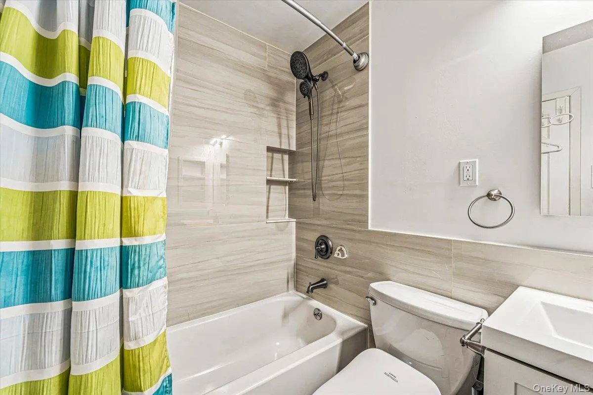 Bathroom featuring a bathtub with a shower, built-in shower niches, and a modern vanity Bathroom featuring a bathtub with a shower, built-in shower niches, and a modern vanity