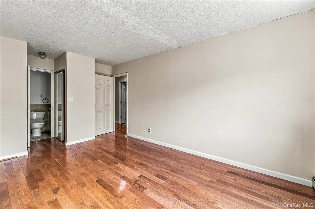 Hardwood flooring, neutral painted walls, white trim, and a built-in closet with mirrored doors Hardwood flooring, neutral painted walls, white trim, and a built-in closet with mirrored doors