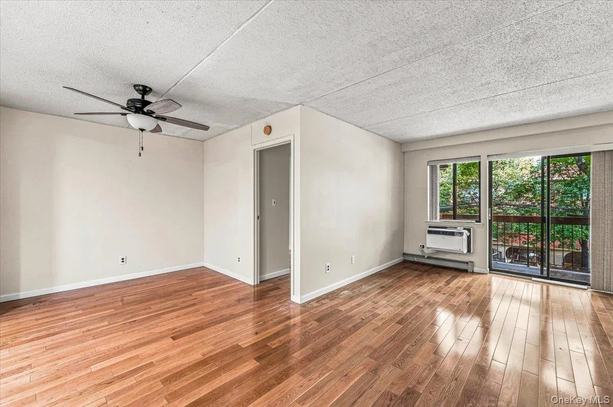 Hardwood flooring, sliding glass door, balcony, ceiling fan, and window air conditioning unit Hardwood flooring, sliding glass door, balcony, ceiling fan, and window air conditioning unit