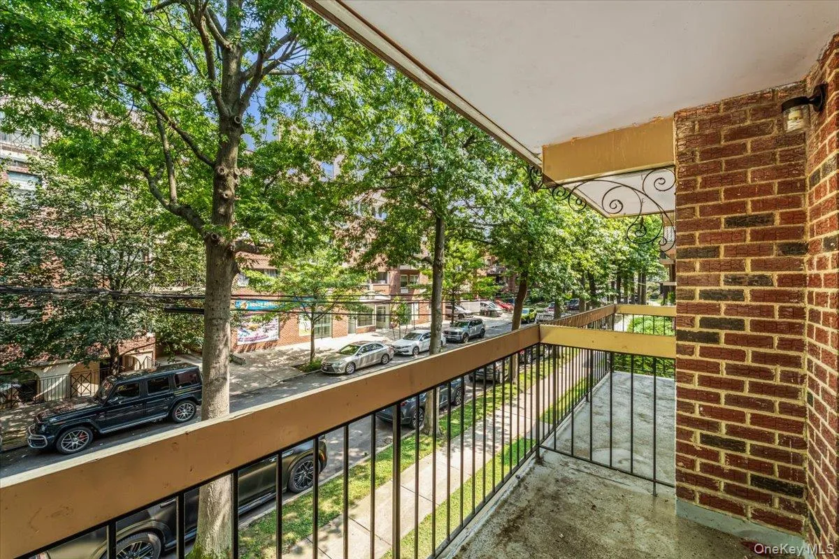 Balcony with a wrought iron railing, brick wall detail, exterior light fixture, and street-level perspective Balcony with a wrought iron railing, brick wall detail, exterior light fixture, and street-level perspective