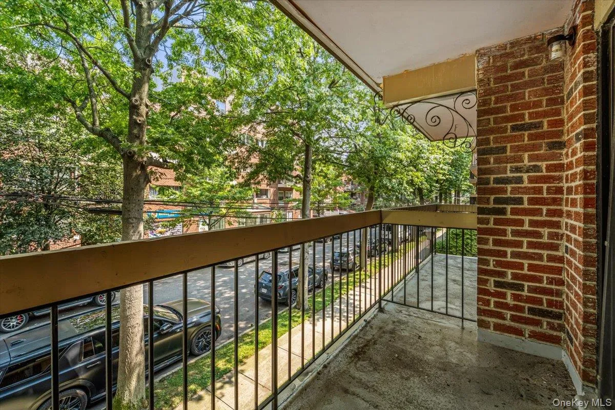 Balcony featuring a brick exterior wall, concrete flooring, and decorative metal railing Balcony featuring a brick exterior wall, concrete flooring, and decorative metal railing