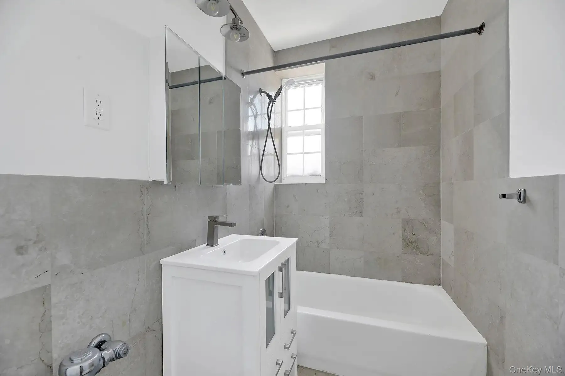 White vanity with integrated sink, modern black faucet, tiled shower/tub combination, and mirrored medicine cabinet White vanity with integrated sink, modern black faucet, tiled shower/tub combination, and mirrored medicine cabinet