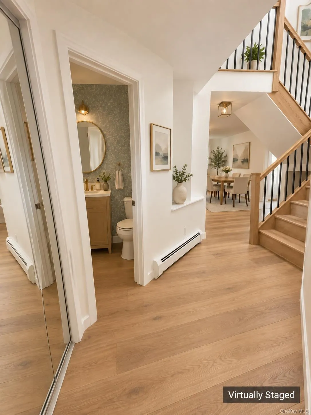 Virtually Staged -Hardwood-finish flooring, staircase with wood treads and black balusters, recessed lighting, and a powder room with a vanity and round mirror Virtually Staged -Hardwood-finish flooring, staircase with wood treads and black balusters, recessed lighting, and a powder room with a vanity and round mirror