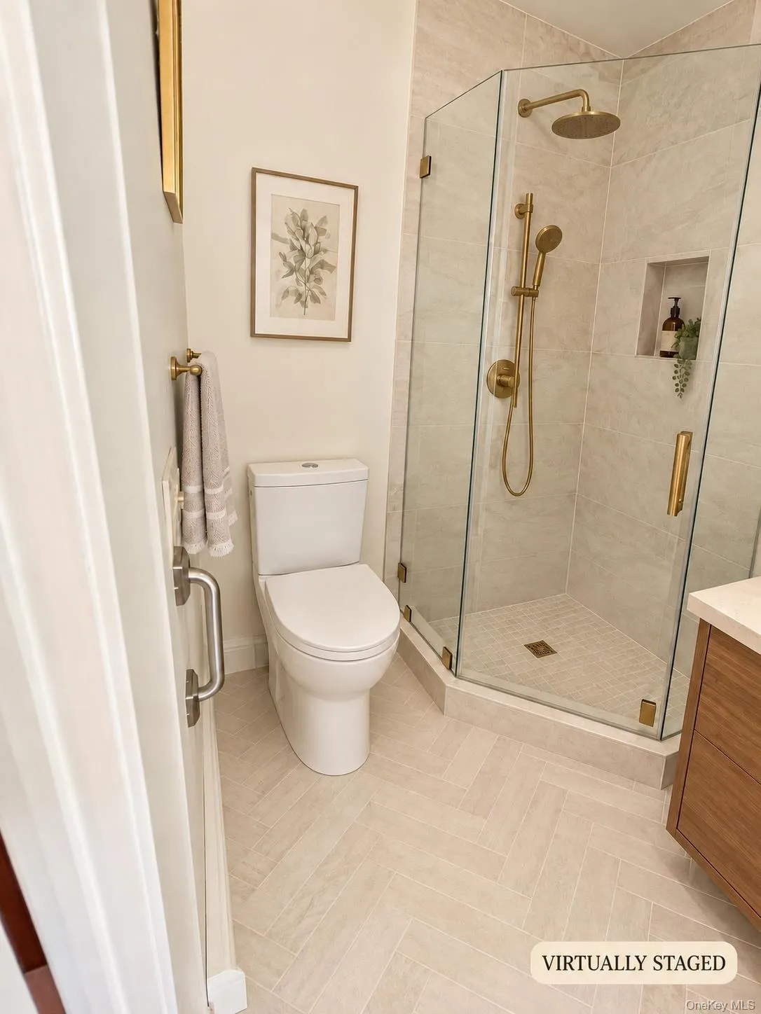 Herringbone-patterned floor tiles, glass-enclosed shower with a built-in niche, and gold-finish fixtures Herringbone-patterned floor tiles, glass-enclosed shower with a built-in niche, and gold-finish fixtures