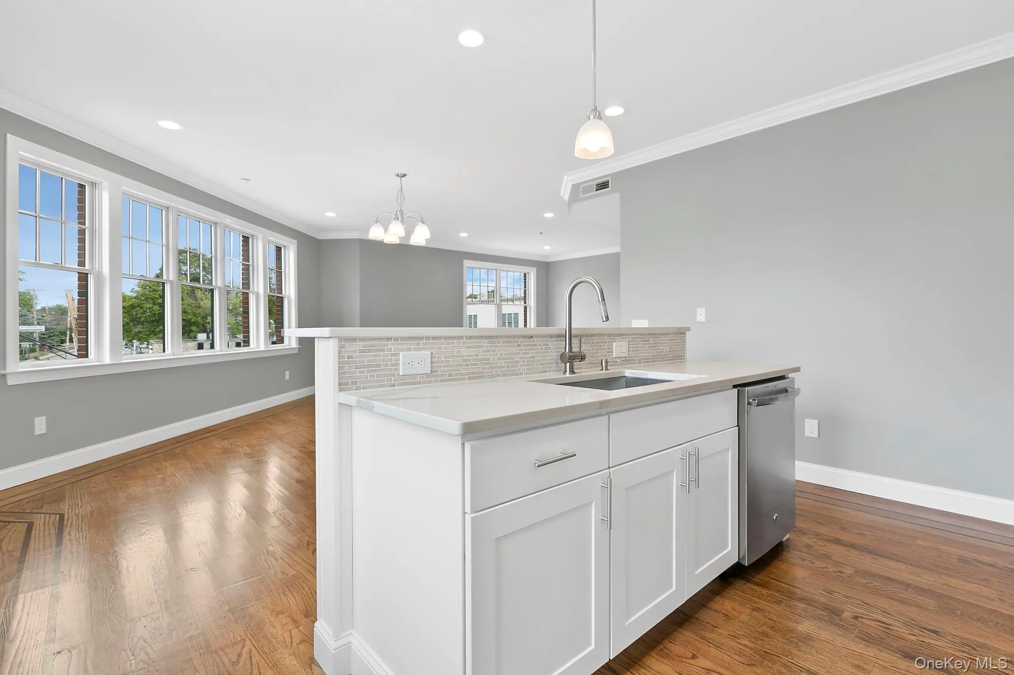 Kitchen with tasteful backsplash, white cabinets, sink, a center island with sink, and dishwasher Kitchen with tasteful backsplash, white cabinets, sink, a center island with sink, and dishwasher