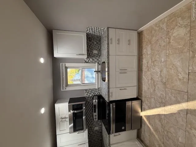 Kitchen with tasteful backsplash, stove, white cabinets, light stone counters, and recessed lighting Kitchen with tasteful backsplash, stove, white cabinets, light stone counters, and recessed lighting