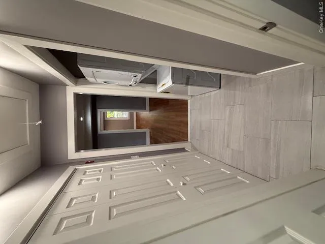 Corridor with stacked washing machine and dryer, attic access, and light wood-type flooring Corridor with stacked washing machine and dryer, attic access, and light wood-type flooring