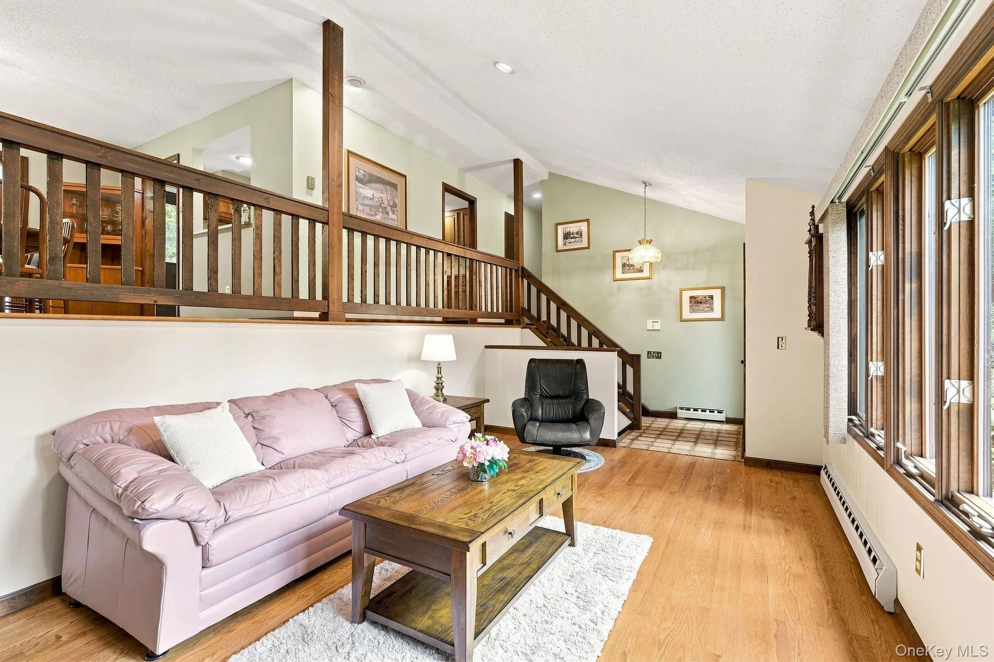 Wood-finish flooring, vaulted ceiling, wood baluster railing, and a window wall Wood-finish flooring, vaulted ceiling, wood baluster railing, and a window wall