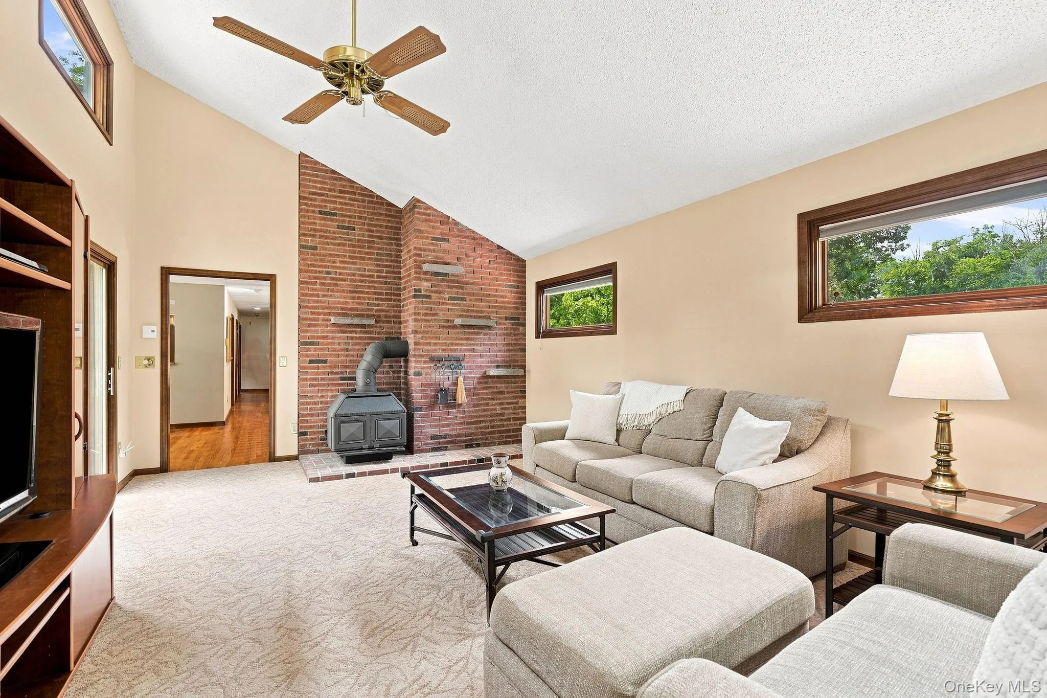Vaulted ceiling with an exposed beam, brick accent wall with a wood-burning stove, and upper transom windows Vaulted ceiling with an exposed beam, brick accent wall with a wood-burning stove, and upper transom windows