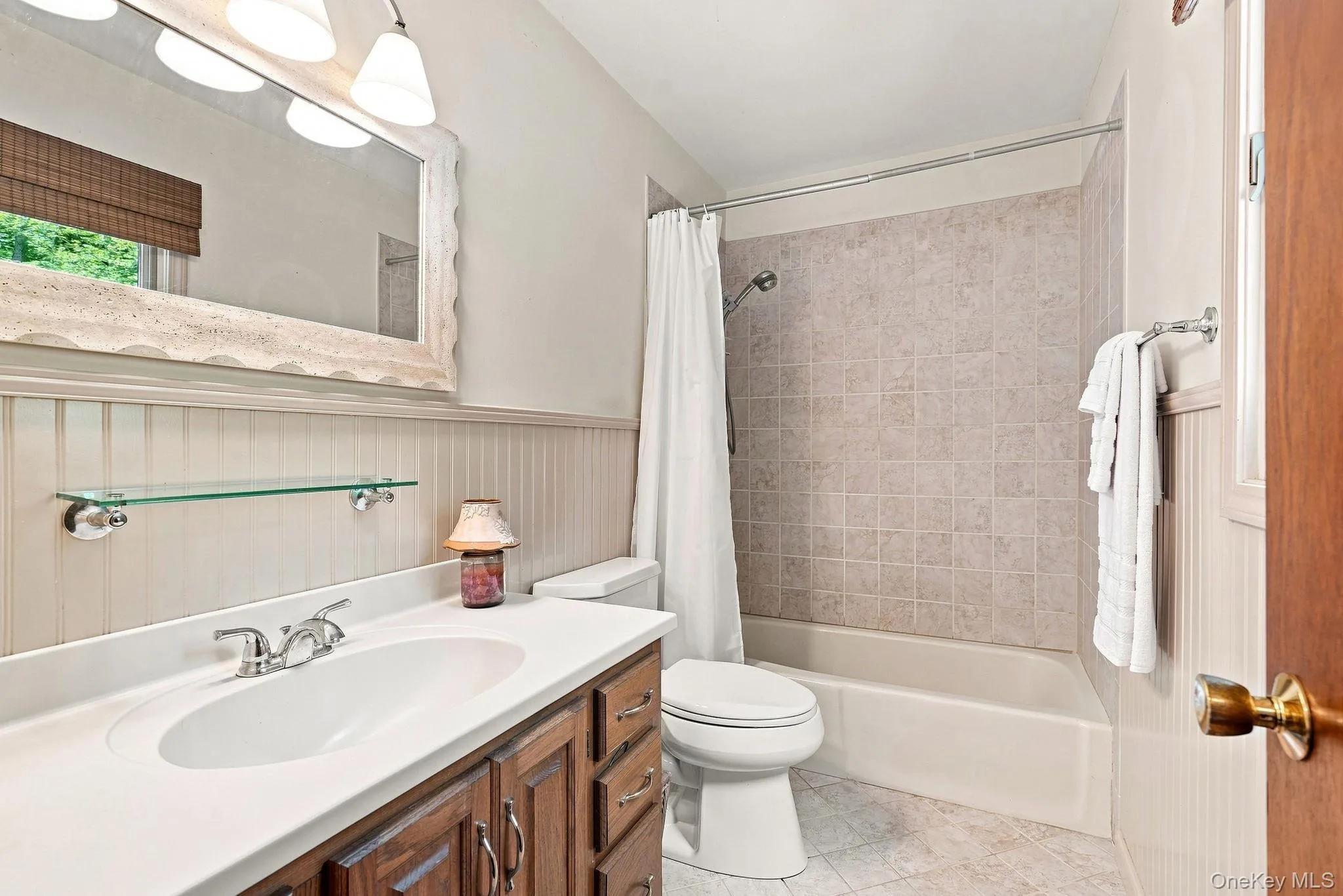 en-suite primary bathroom featuring a wood-finish vanity with dual-sink configuration, white quartz countertop, and chrome faucetry en-suite primary bathroom featuring a wood-finish vanity with dual-sink configuration, white quartz countertop, and chrome faucetry