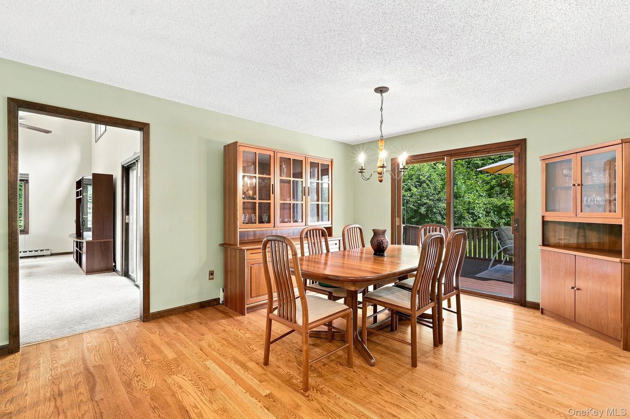 Wood-finish flooring, sliding glass door to exterior deck, and a classic chandelier Wood-finish flooring, sliding glass door to exterior deck, and a classic chandelier