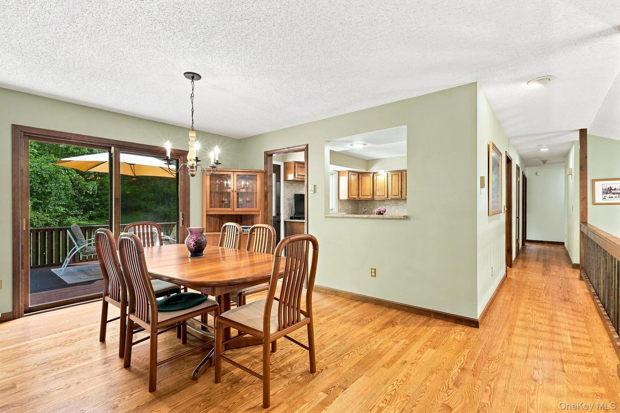 Hardwood flooring throughout, sliding glass door to exterior deck, kitchen pass-through window, and overhead chandelier Hardwood flooring throughout, sliding glass door to exterior deck, kitchen pass-through window, and overhead chandelier