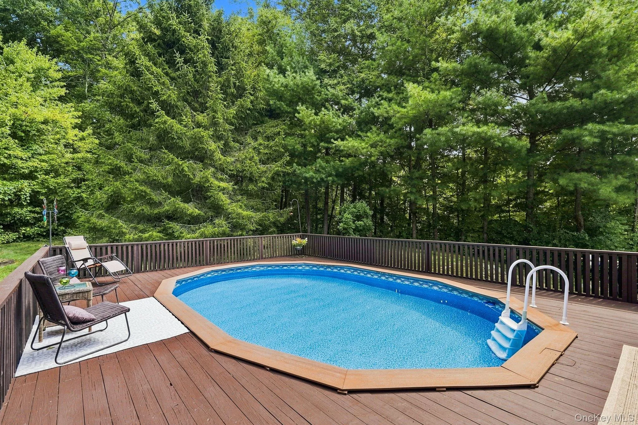 Expansive wood-finish deck surrounding a pool w/fencing Expansive wood-finish deck surrounding a pool w/fencing