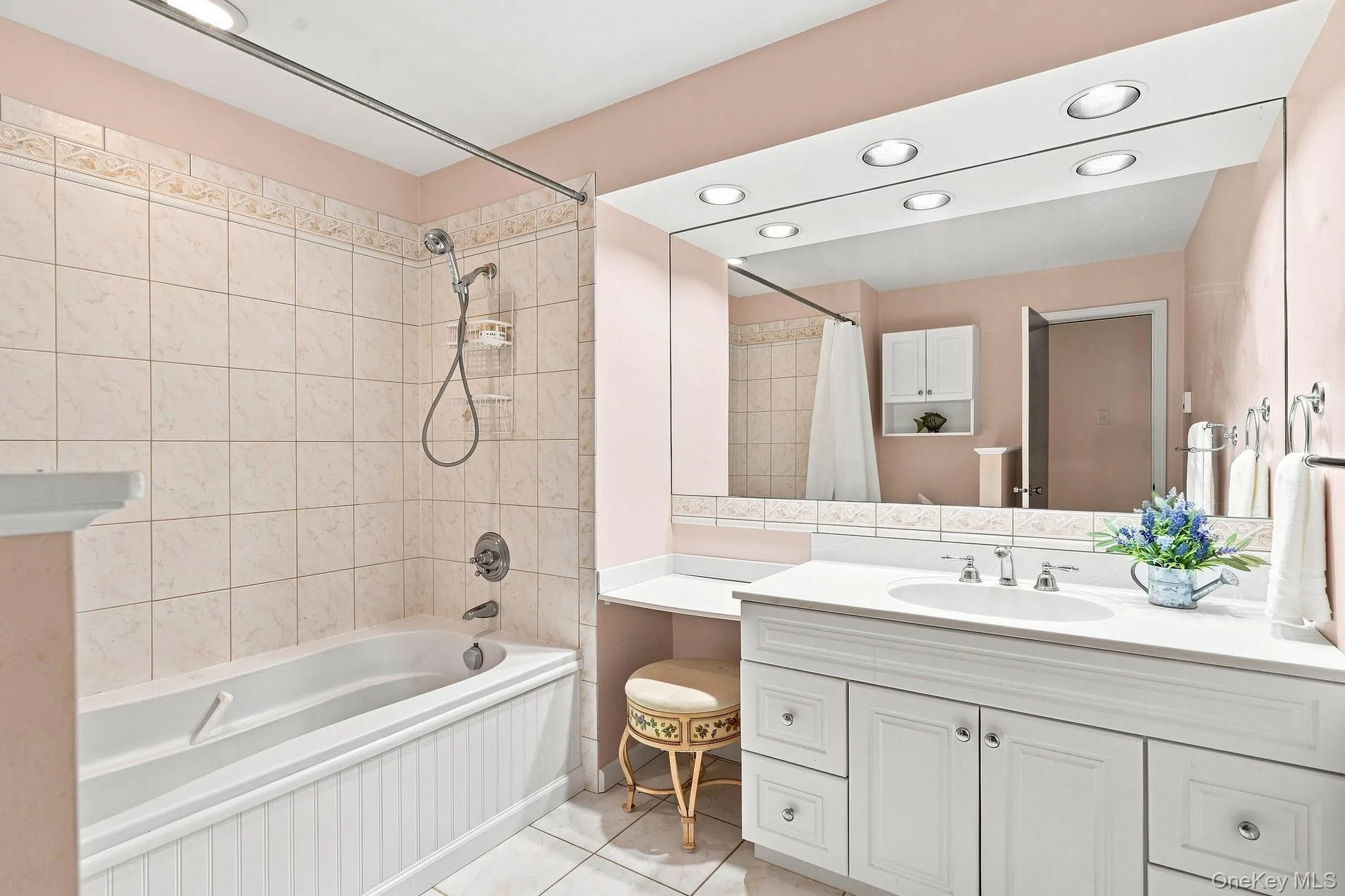 Hall Bathroom featuring a full-sized bathtub with tiled surround, a vanity with an integrated sink and storage cabinetry, a large wall-mounted mirror, and recessed ceiling lighting Hall Bathroom featuring a full-sized bathtub with tiled surround, a vanity with an integrated sink and storage cabinetry, a large wall-mounted mirror, and recessed ceiling lighting